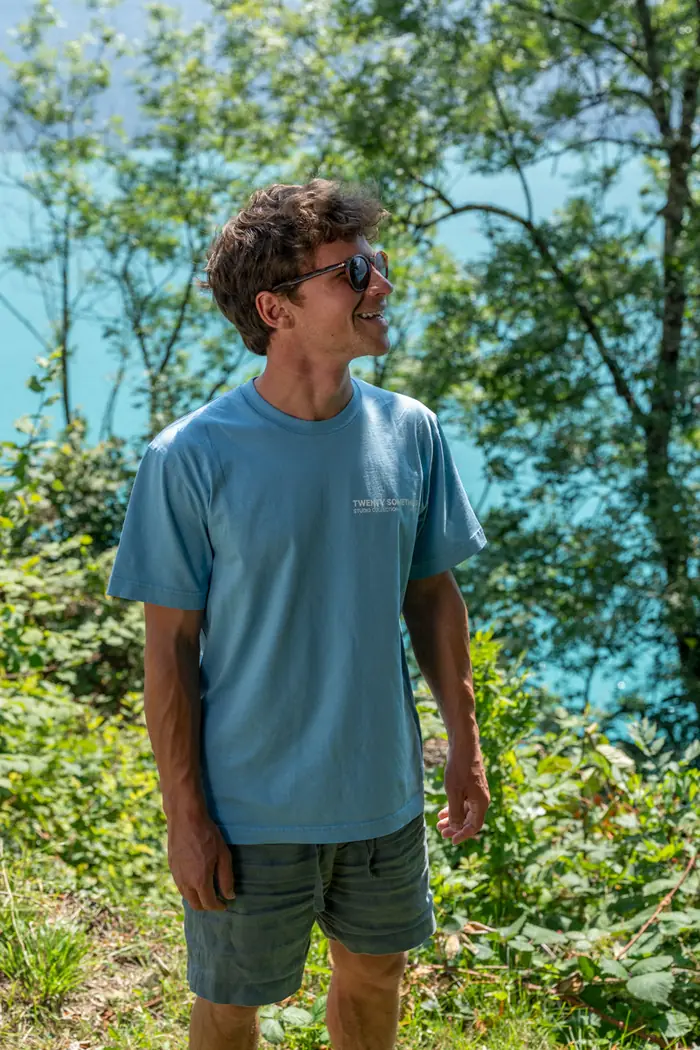Mann im hellblauen Tee lacht am Bergsee